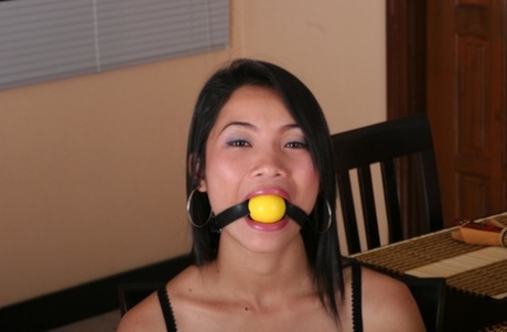 Asian girl struggles against a ball gag while tied to a kitchen chair 89079859