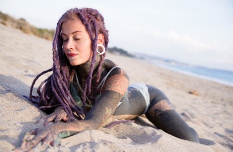Heavily tattooed girl releases tiny tits from bikini top on a sandy beach 99907499