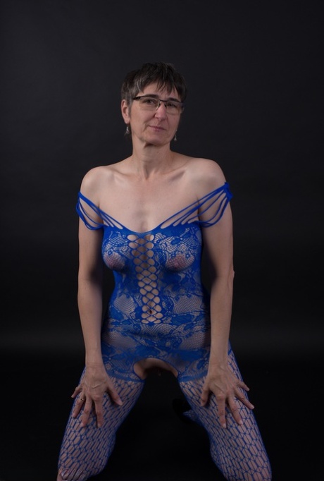 Older model poses in a crotchless bodystocking and heels with her glasses on 60077206
